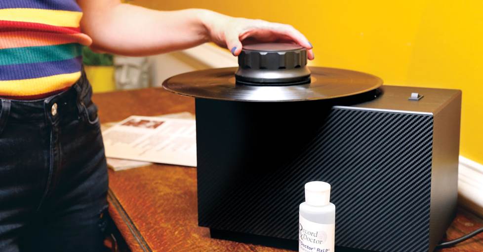 A person using the Record Doctor VI 20th Anniversary Edition record cleaning machine to clean an record.