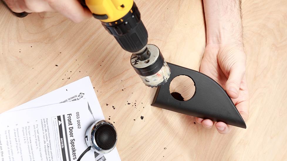 hands drilling a whole in a small plastic trim piece for tweeter