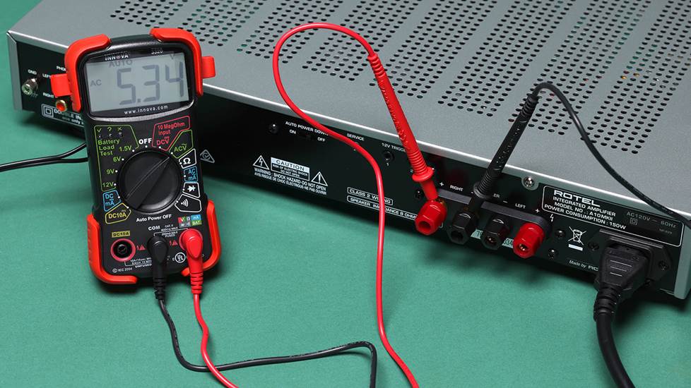 Multimeter with probes connected to integrated amp speaker terminals