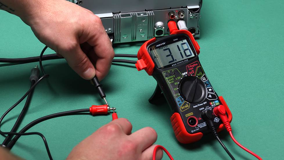 Multimeter with probes connected to RCA plug coming from a car steareo head unit