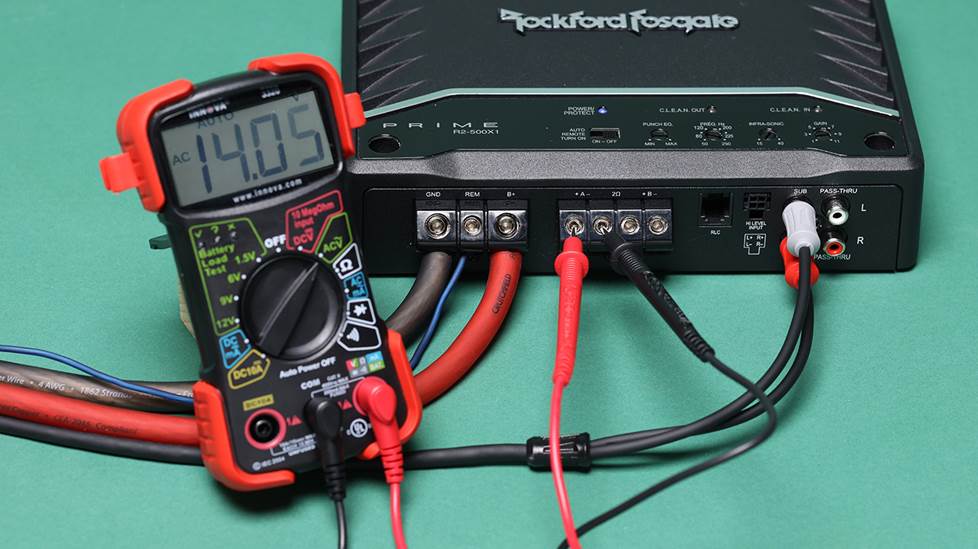 Multimeter with probes connected tocar amplifier speaker terminals
