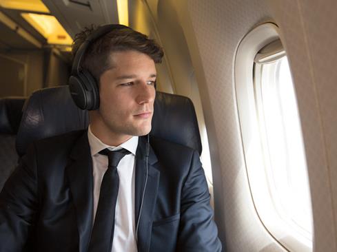 Man wearing Bose QC25 headphones on a plane