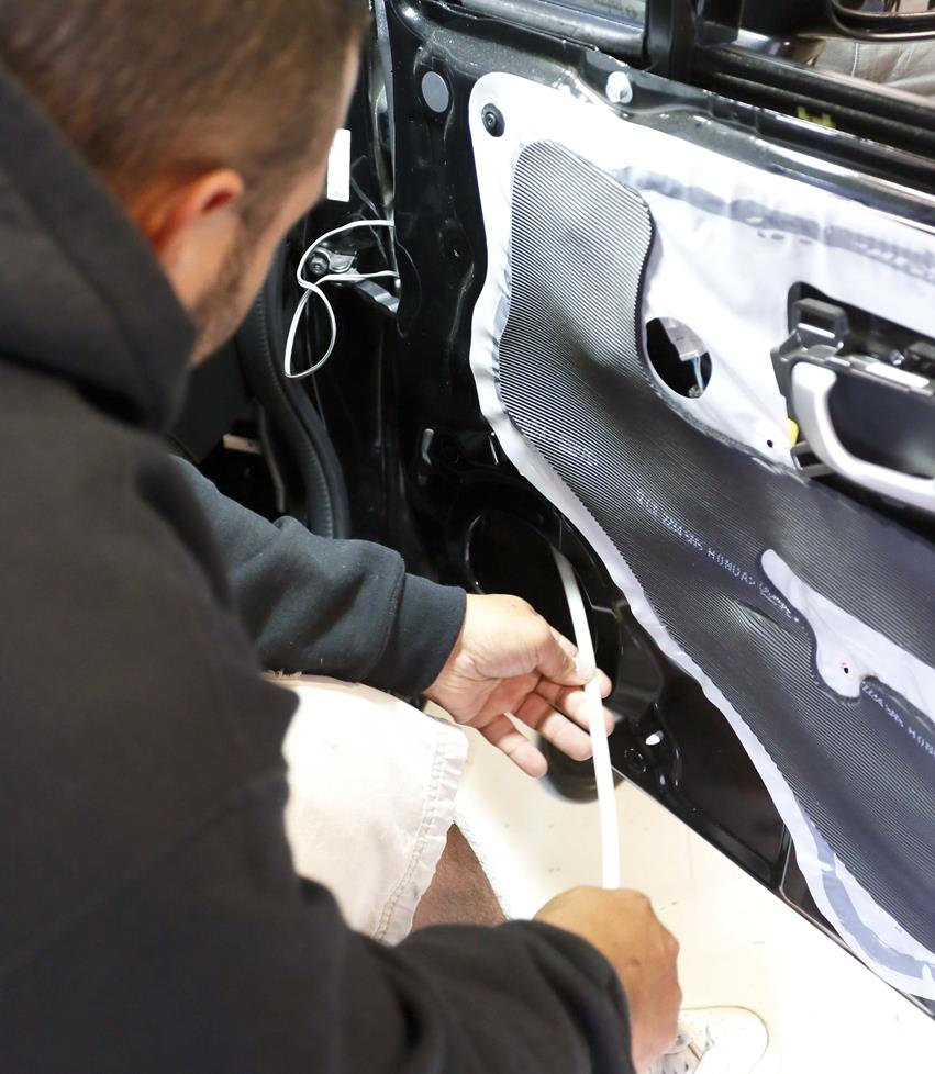 Steven runs the speaker wire through the door grommet.