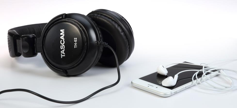 Studio headphones next to iPhone and stock earbuds