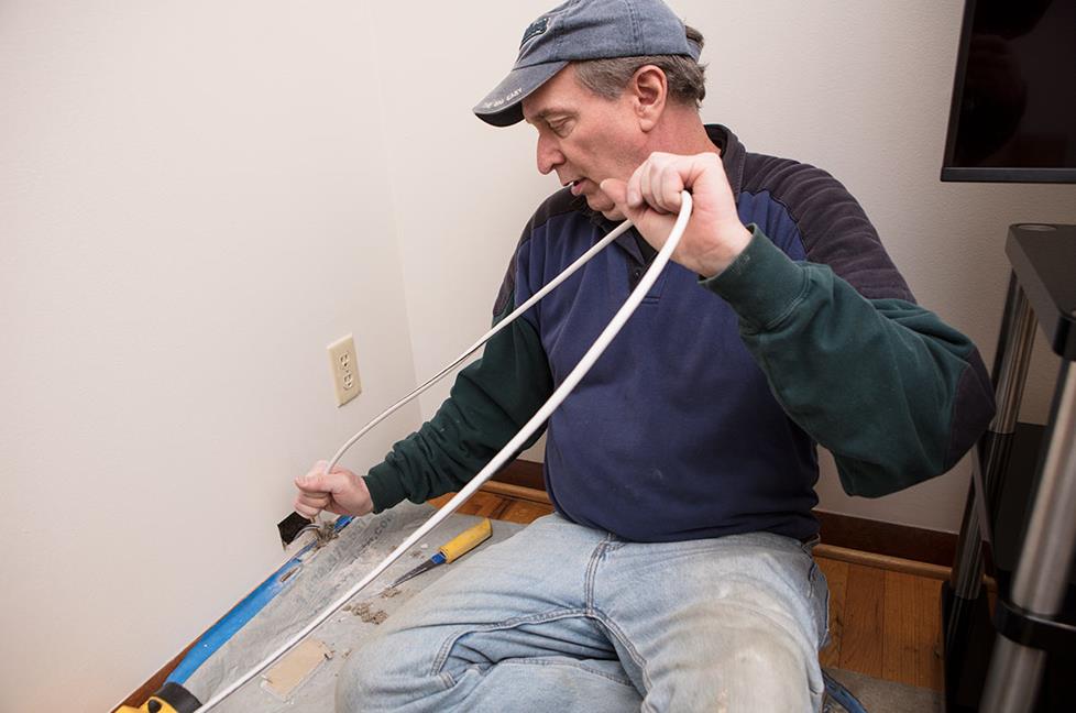 Installer pulling cable through wall