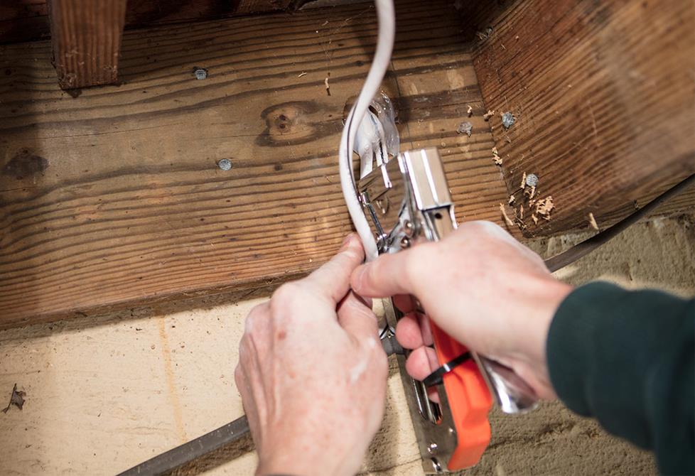 Installer stapling cable to framing