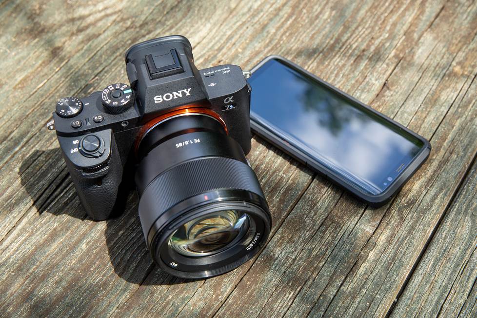 Sony mirrorless camera next to smartphone for size comparison
