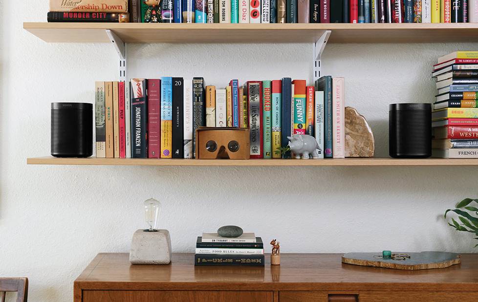 Two Sonos speakers on a bookshelf