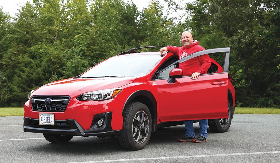 J.R. standing next to his red Subaru