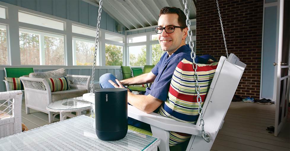 Man sitting outside on porch with speaker