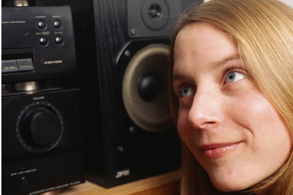woman with her ear next to a speaker