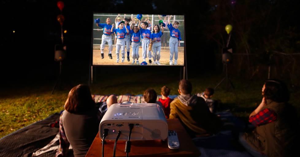 A family watching a movie on a projector in their back yard