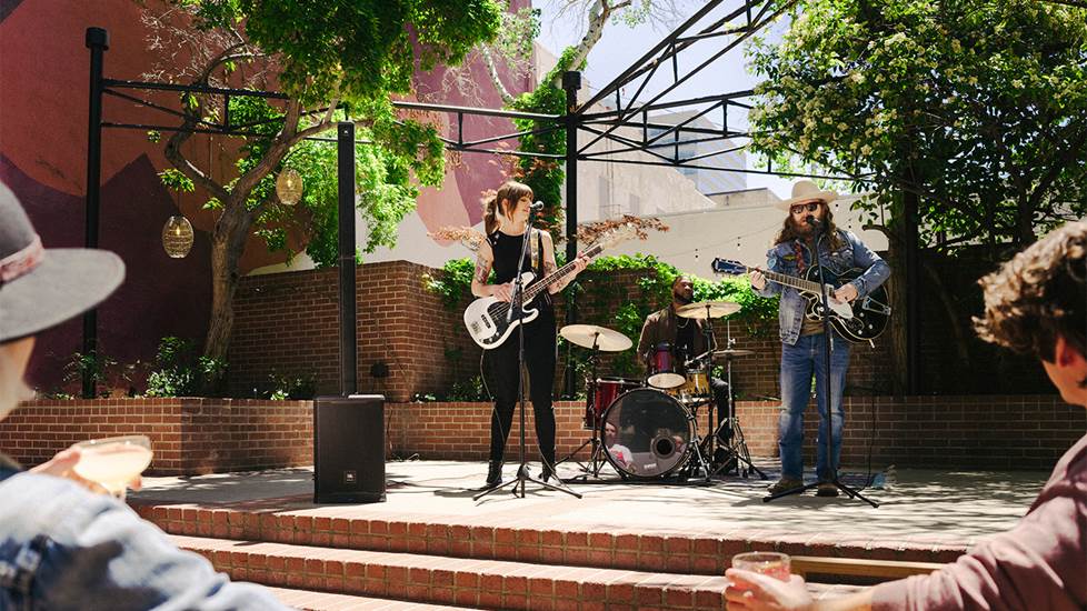Small band playing on an outdoor stage with two mics for vocals