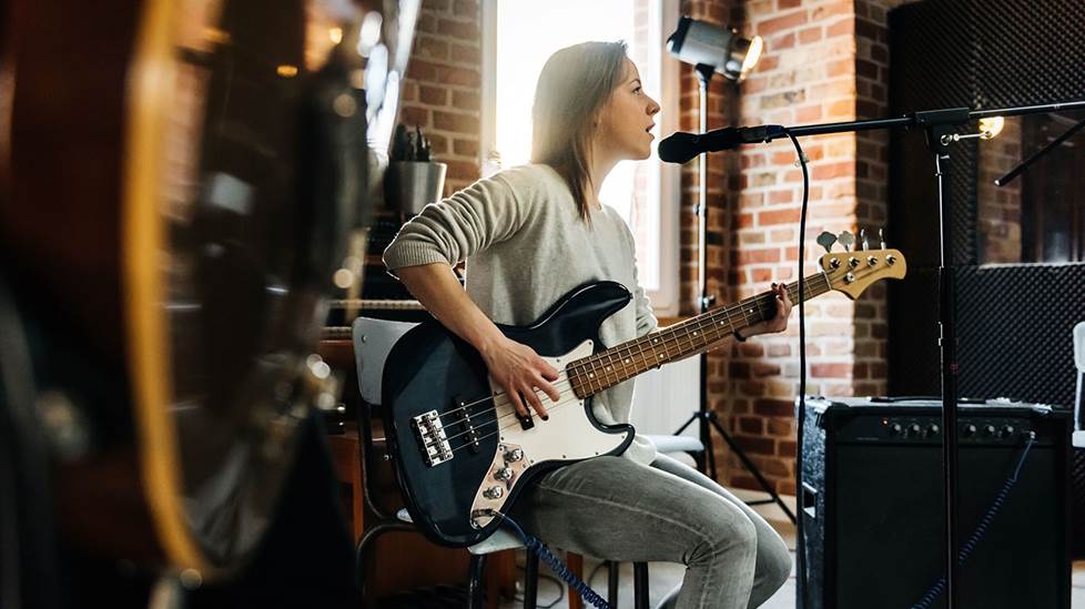 bass player in a band singing into a microphone on a boom stand