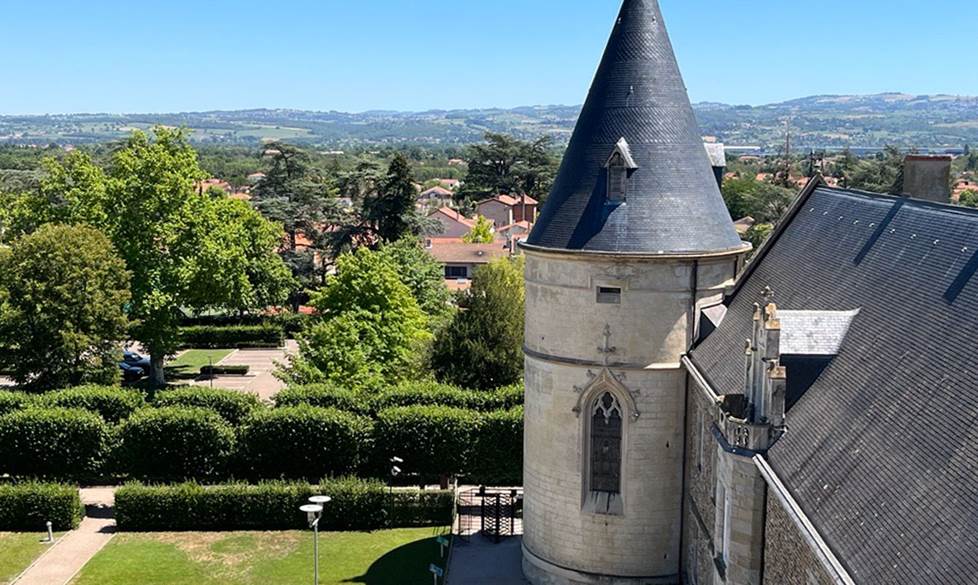 Photo of a green French countryside in St. Etienne with part of a castle in the foreground to the right.