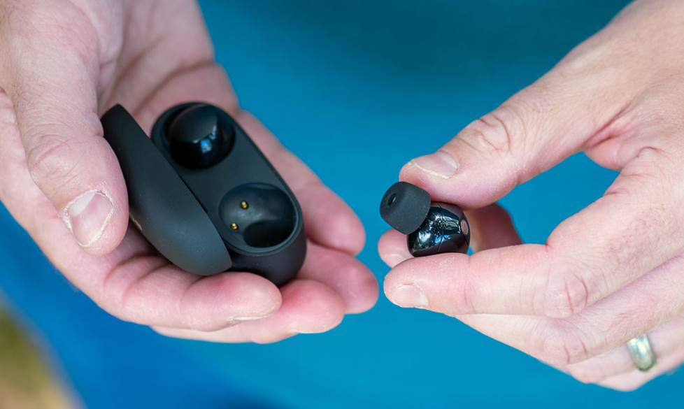 Hands holding an earbud and earbud case.
