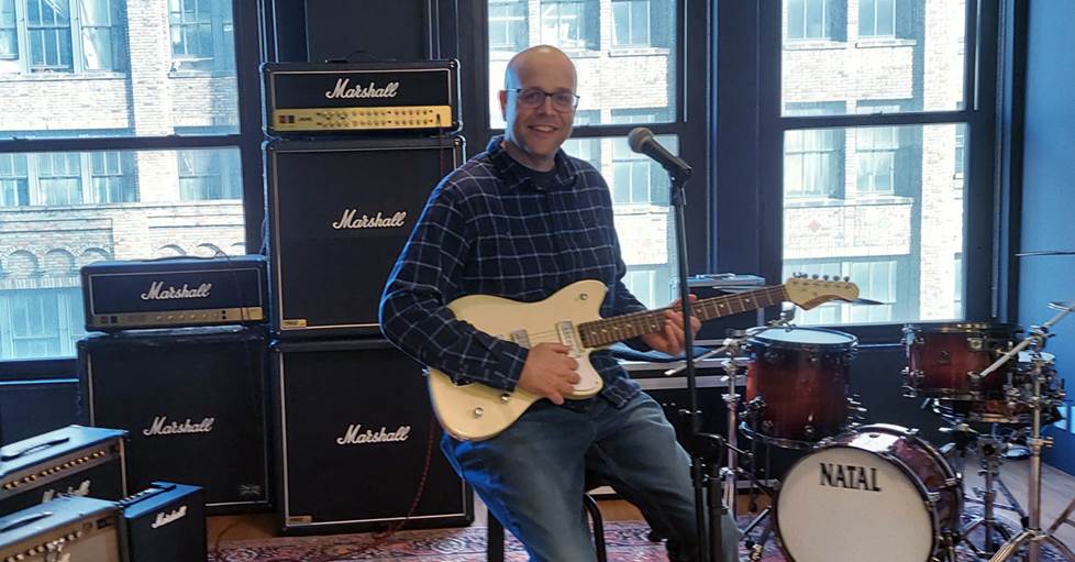 Jeff playing guitar with several Marshall amps behind him