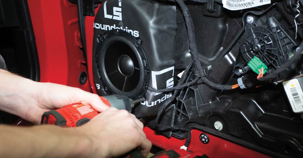 Installing car speakers in a Dodge Charger with sound damping material behind them.
