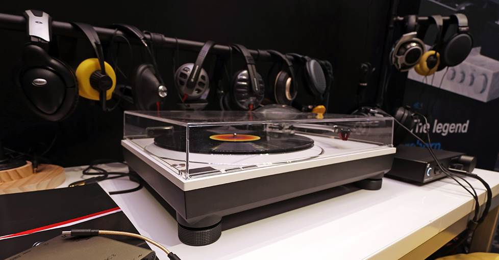 A white turntable with several headphones hanging around it.
