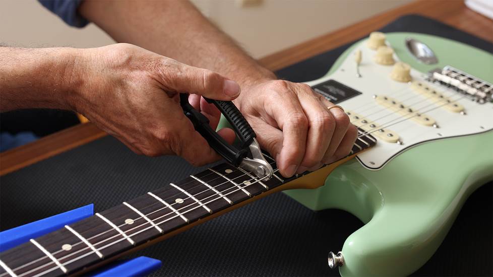 hands cutting a guitar string with wire clipper