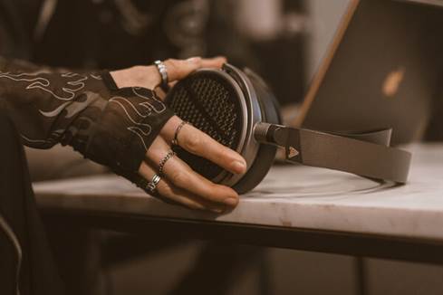 Mixing engineer holding MM-100 headphones next to laptop