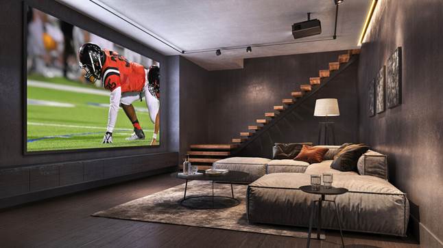 Cozy dark viewing room with plush couch and football on projector screen